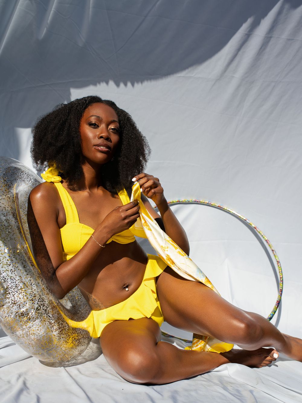 Artistic portrait with yellow swimwear against white fabric backdrop.