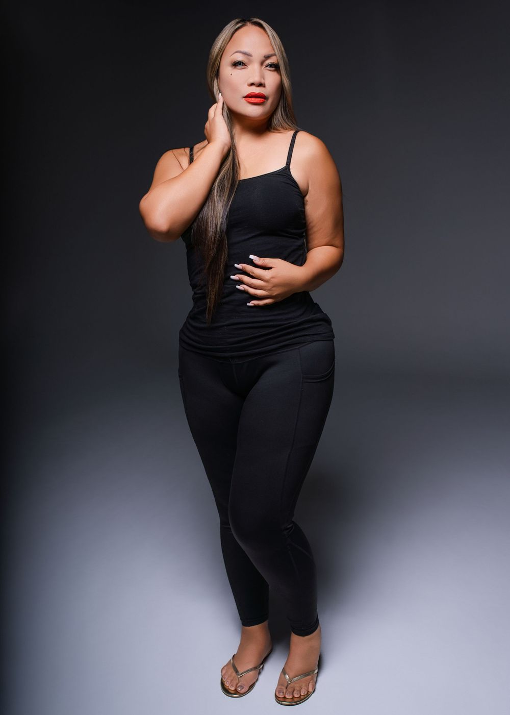 Fashion portrait of a model in black athletic wear against dark background.