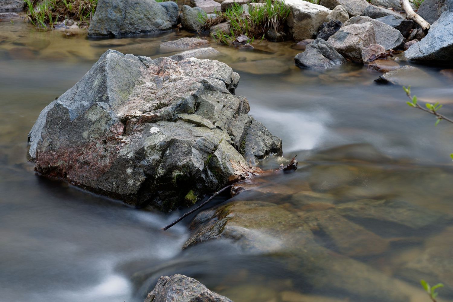 Beautiful cascading waterfall flows over rocky terrain in a backlit sunlit forest setting.