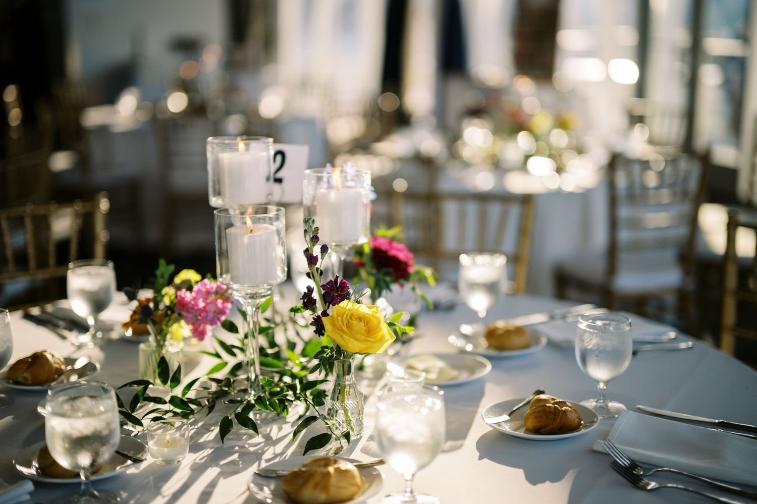 Elegant wedding reception table set with floating candles, colorful flower centerpieces and formal place settings.
