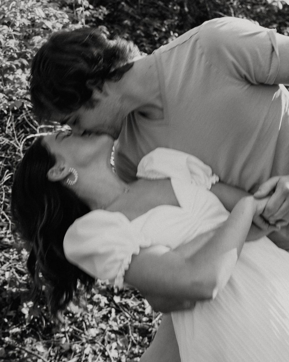 Romantic black and white portrait of couple in intimate embrace outdoors.