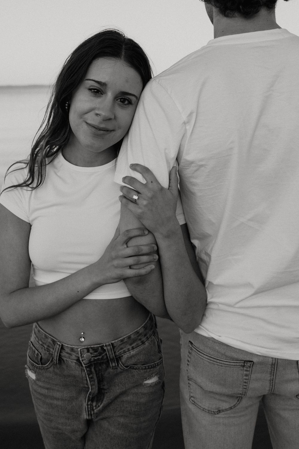 Black and white portrait of couple in casual wear on beach.