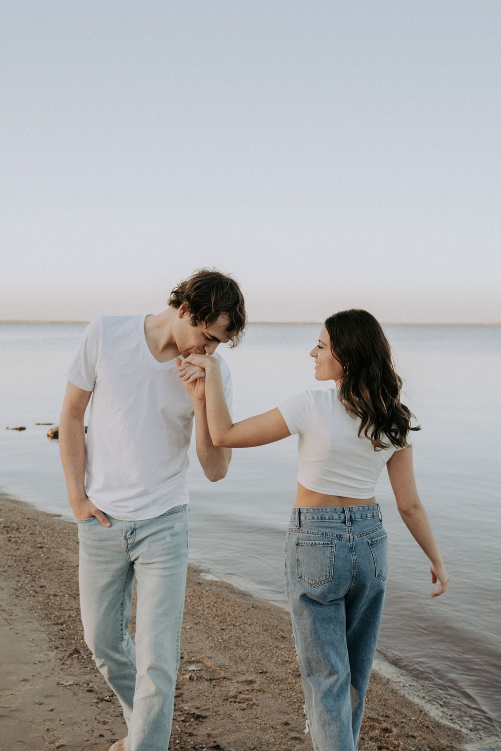 Playful couple in matching outfits sharing a tender moment by the water.