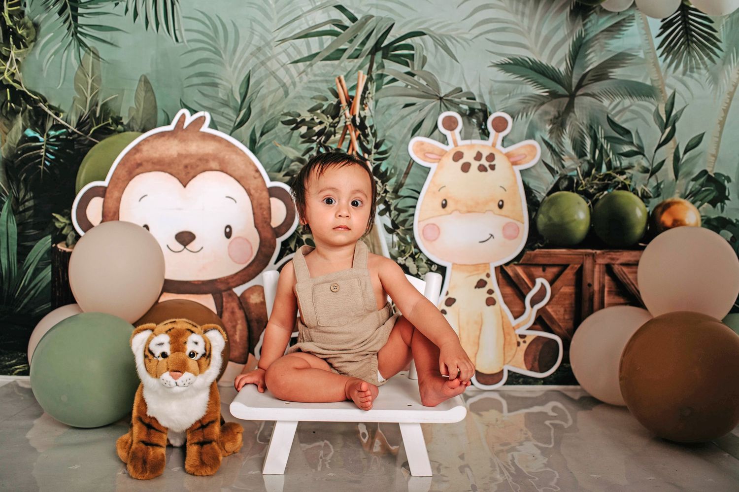 Safari themed birthday setup with monkey and giraffe cutouts against tropical backdrop.