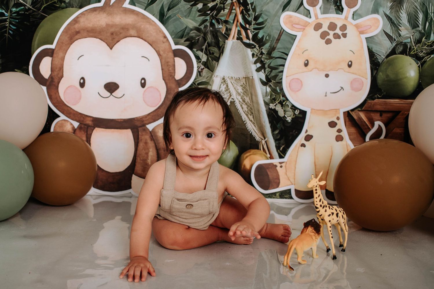 Jungle-themed photo setting with large monkey and giraffe cutouts, brown and green balloons.