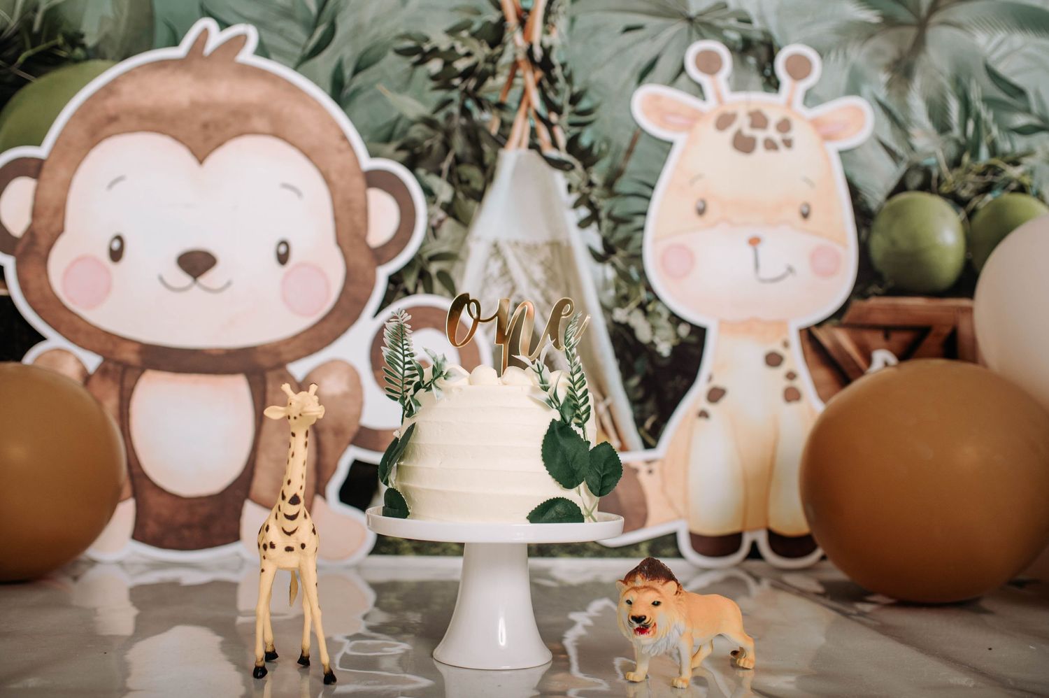 Safari party decoration setup with cake stand, toy animals, and cartoon monkey and giraffe cutouts.