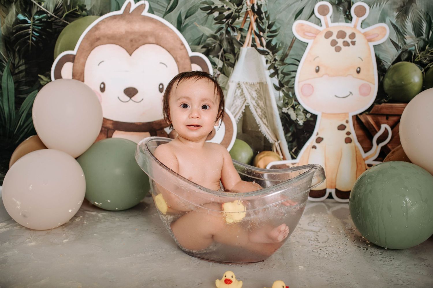 Safari-themed setup featuring clear bowl prop, monkey and giraffe wall art, and green balloon arrangement.