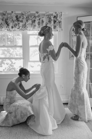 Wedding dresses being fitted and adjusted in a bright sunlit room.