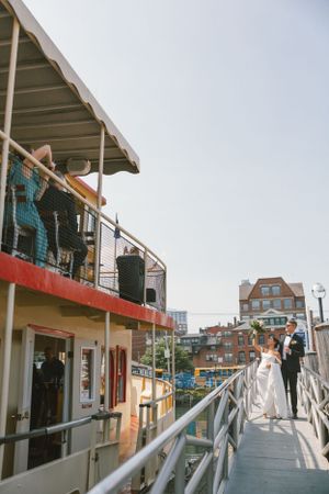 View of an empty boat dock with white railings and buildings in the background.