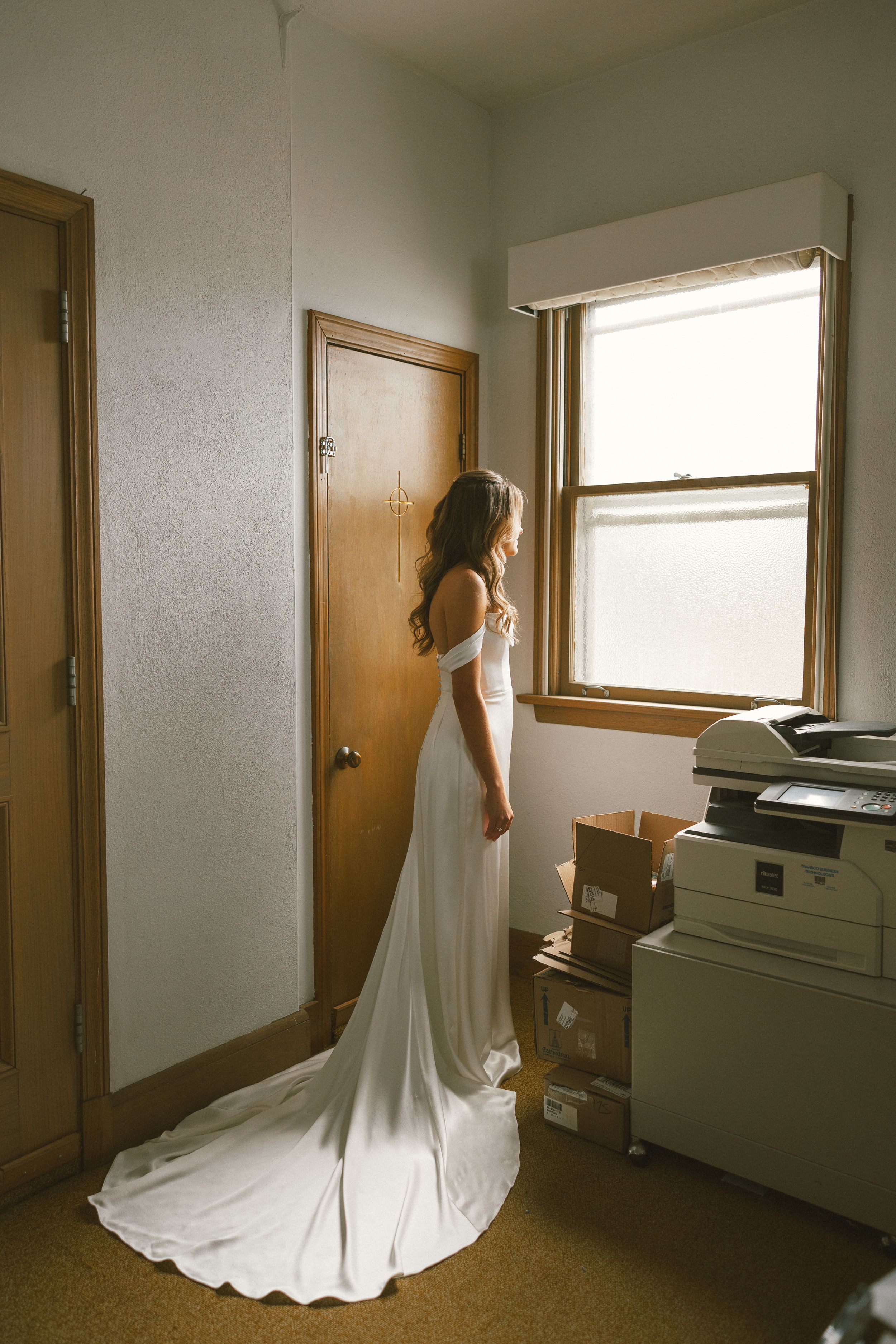 Elegant white wedding dress with a long train photographed in natural light indoors.