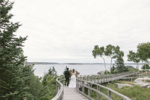 Scenic coastal boardwalk with water views and evergreen trees.