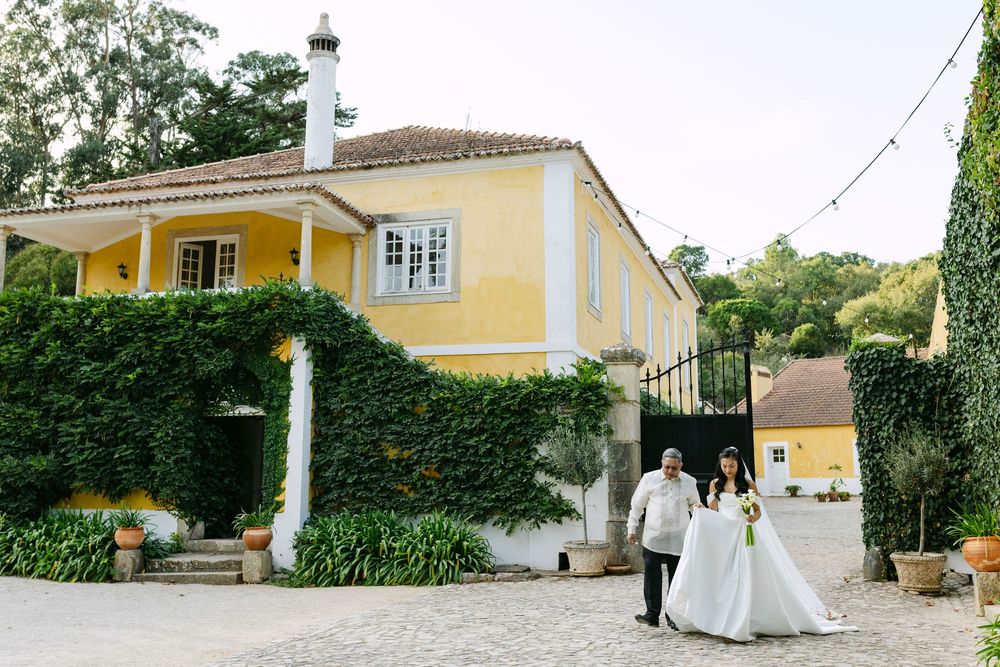 Bride walking down the aisle with father figure during outdoor wedding ceremony in Lisbon