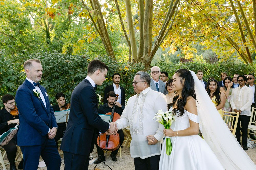 Bride and groom holding hands during wedding ceremony surrounded by guests in Lisbon