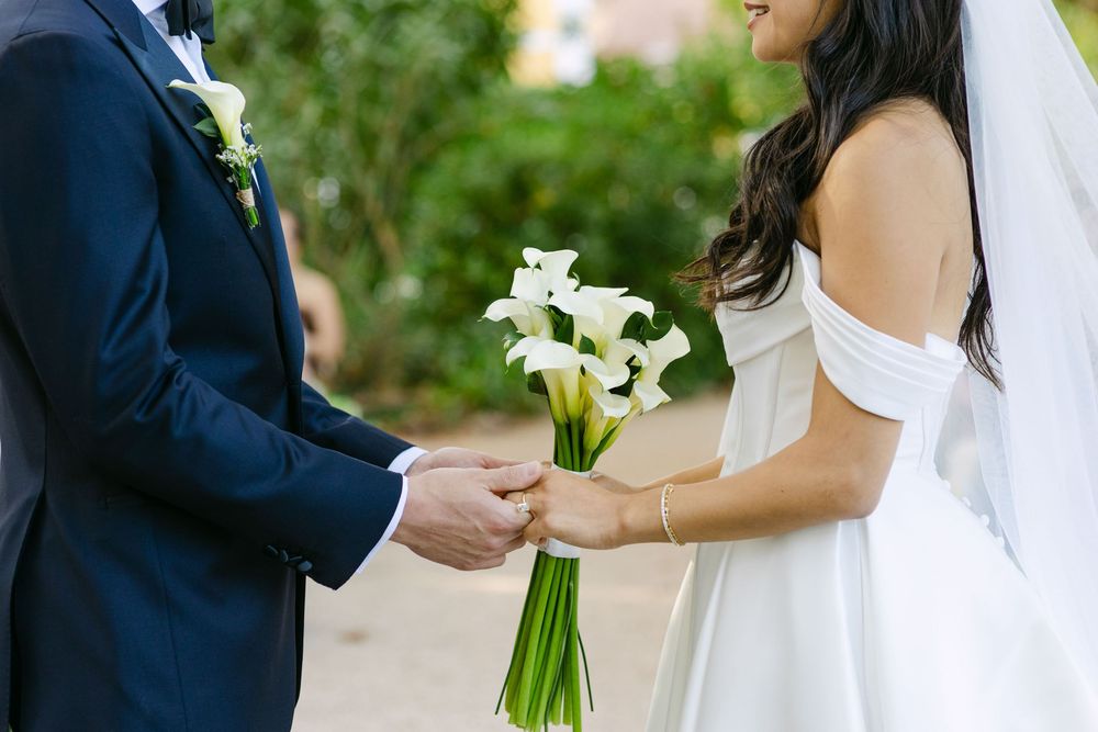 Close up of bride and groom hands holding bouquet during outdoor wedding ceremony in Lisbon