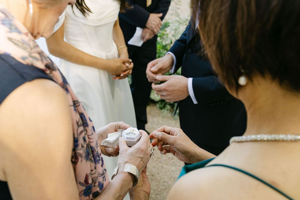 Close-up of hands exchanging wedding rings during an indoor ceremony.