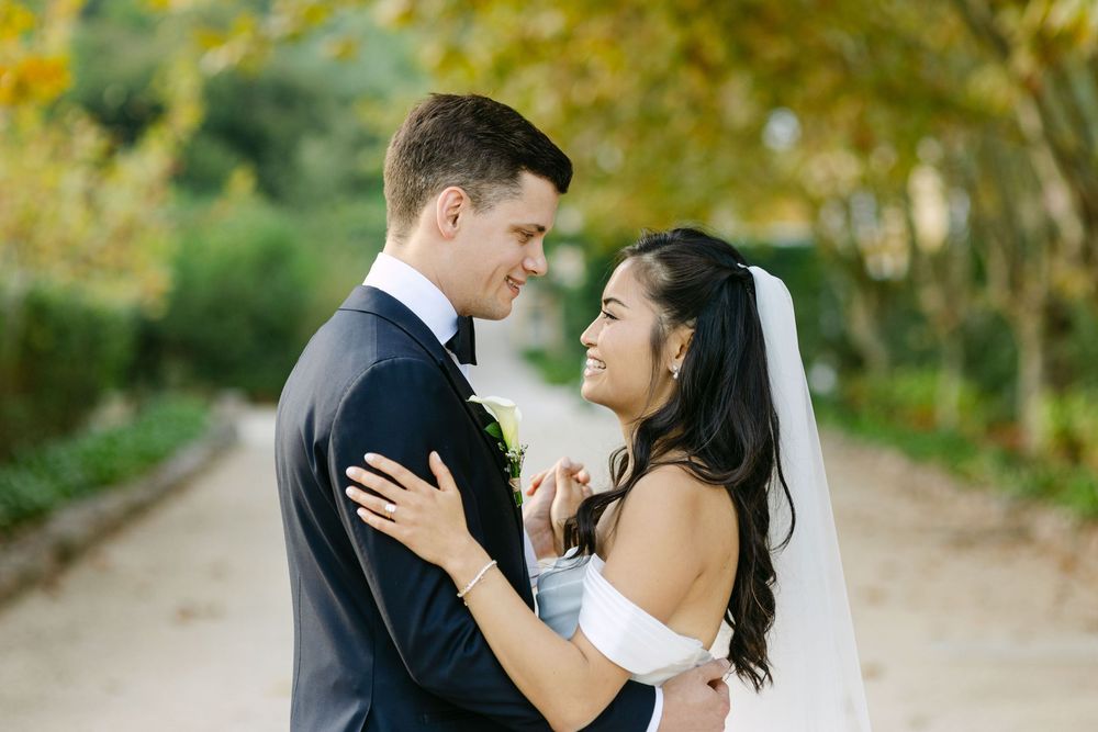 A couple shares romantic moments in a garden setting during their wedding day celebration.