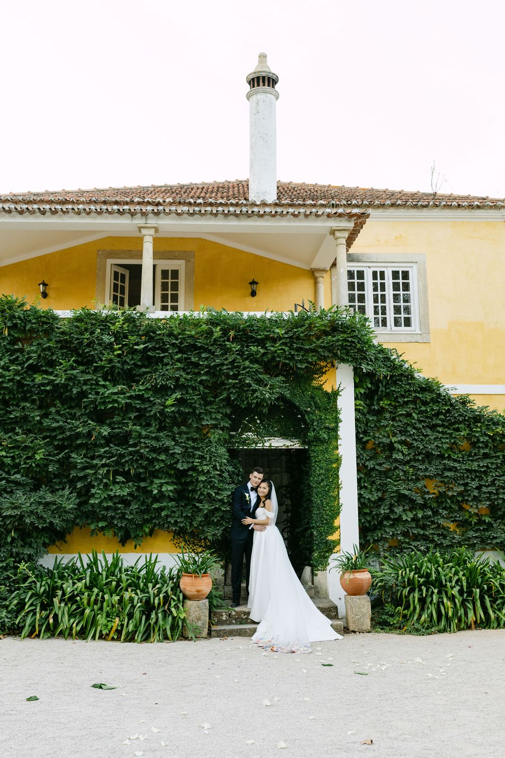 Bride and groom standing in doorway covered in greenery at Quinta Nova do Hespanhol Lisbon wedding venue