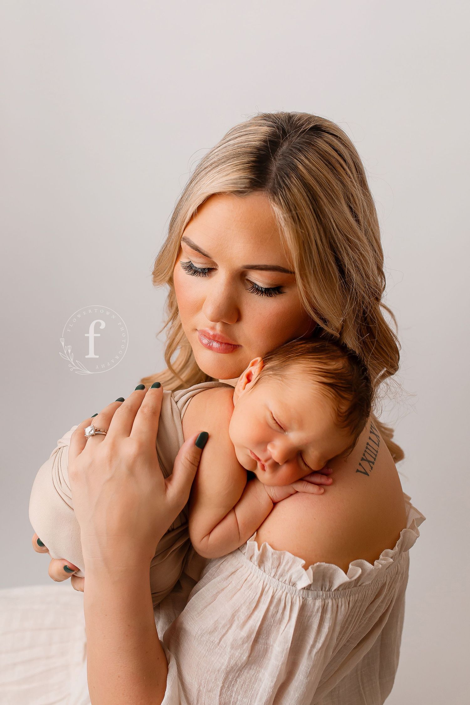 Mother holding sleeping newborn baby on her shoulder during studio portrait session at Flowertown Photography