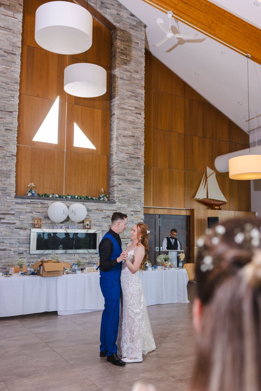 A couple shares their first dance together in an elegant venue with stone walls and wooden accents.