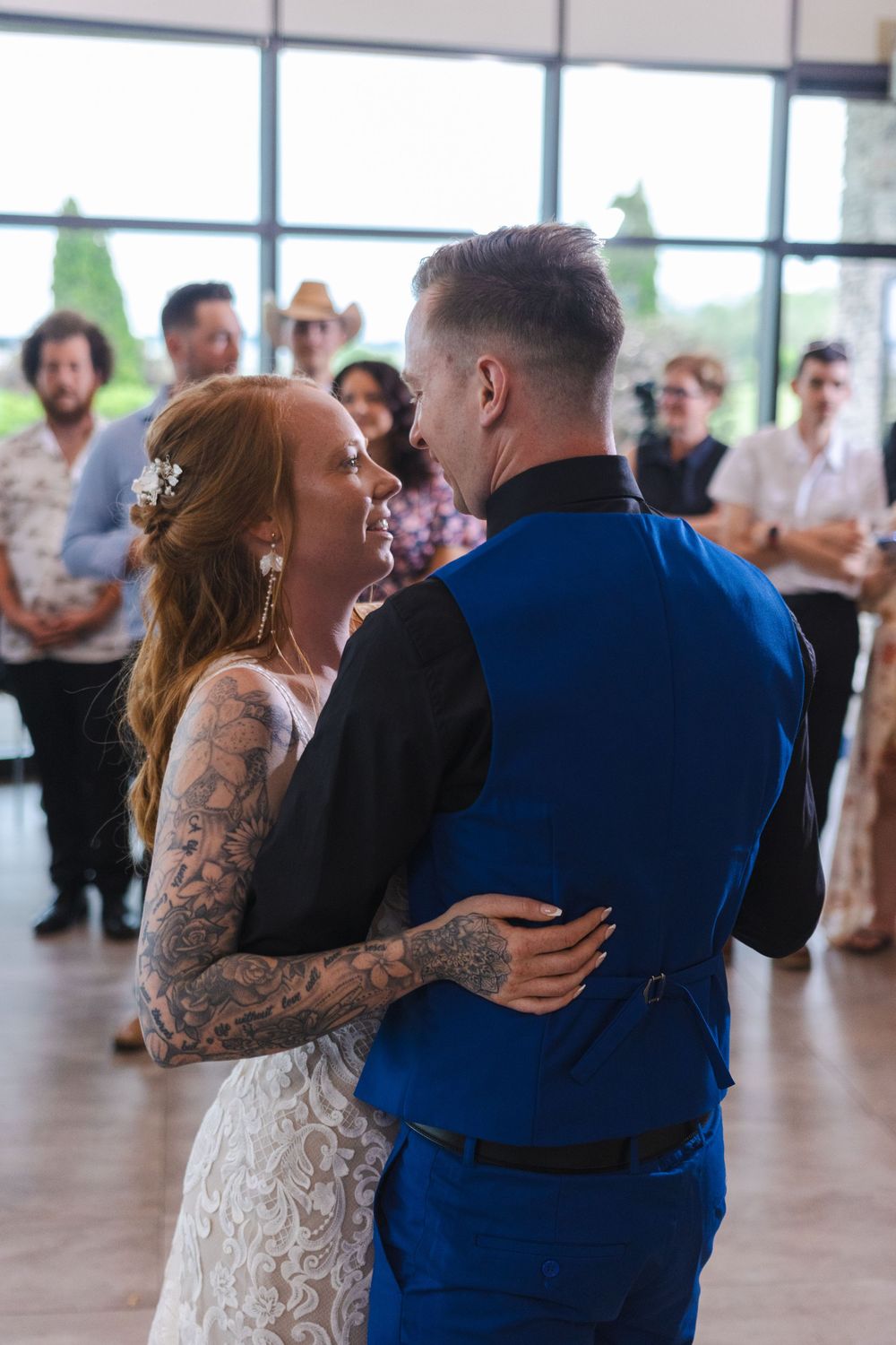 A couple shares a joyful dance together at a wedding reception in a bright venue with large windows.