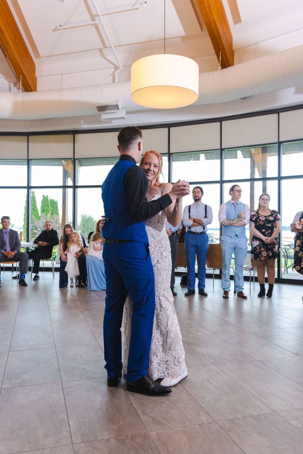 Couples dancing together in a bright modern event space with wooden beams and large windows.