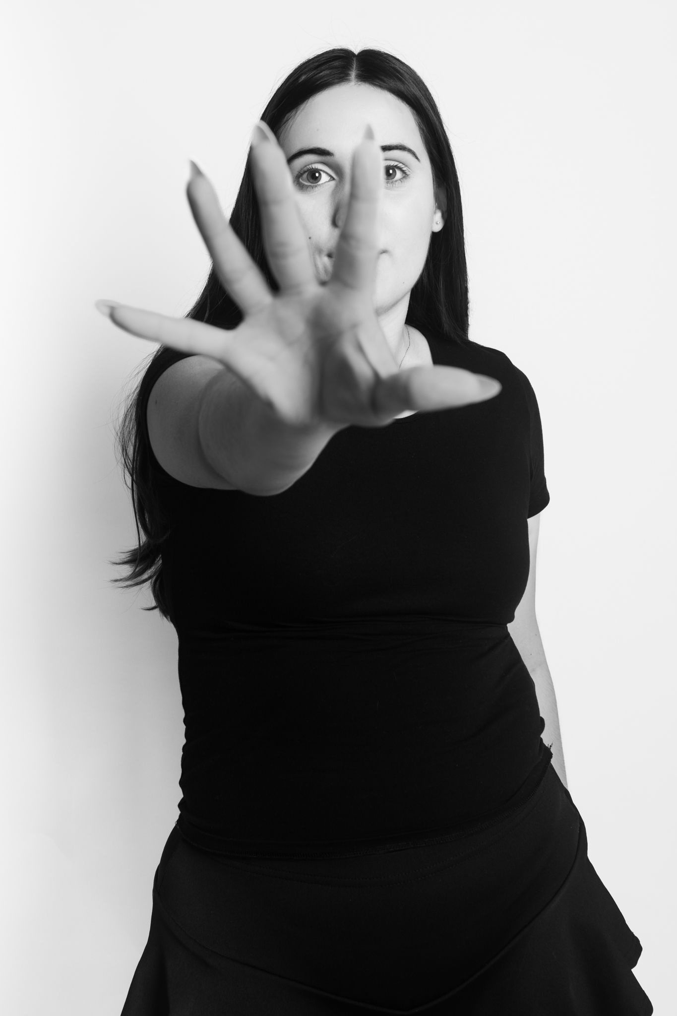 Black and white portrait of woman in black dress extending hand toward camera.