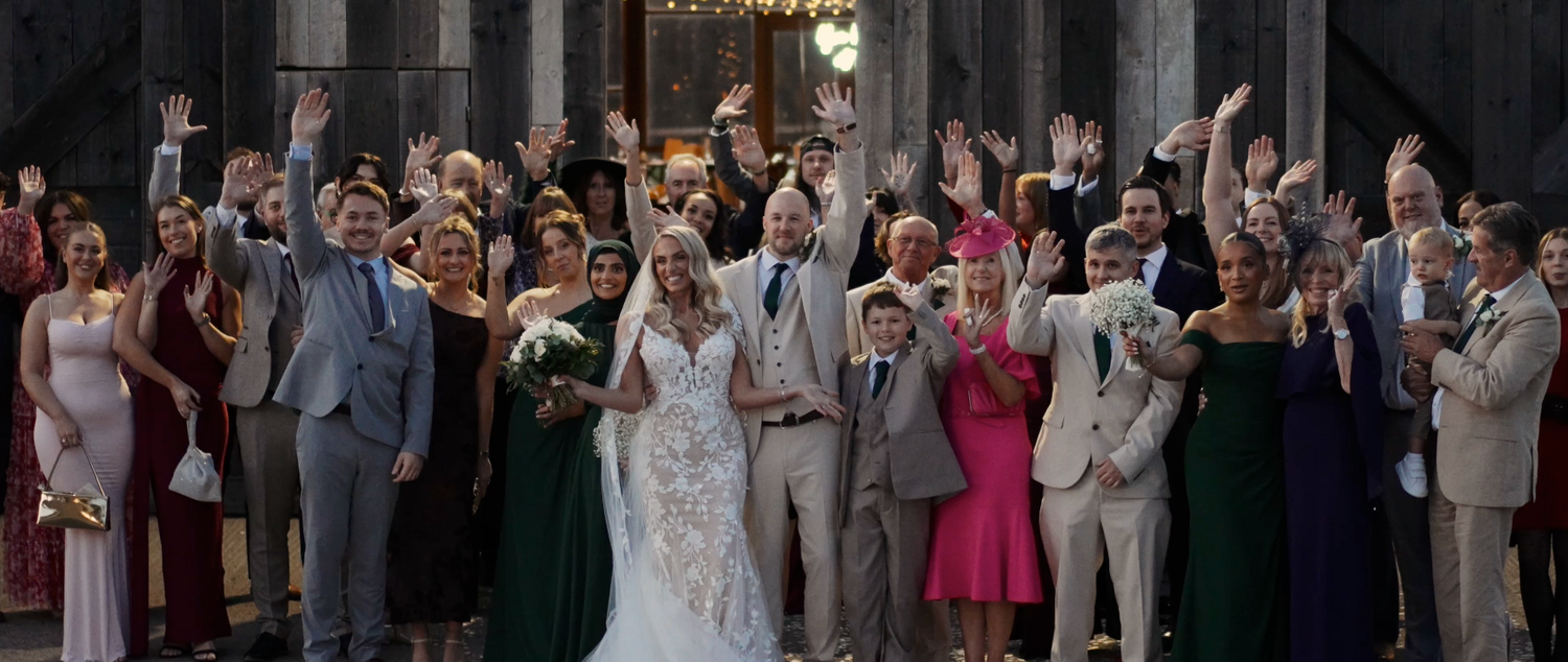Large group of wedding guests gathered for a celebratory moment in an elegant venue.