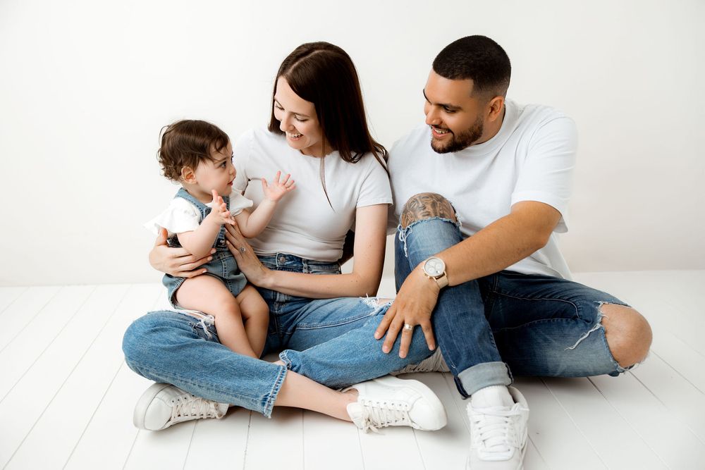 family of three, wearing jeans and white shirts, studio session