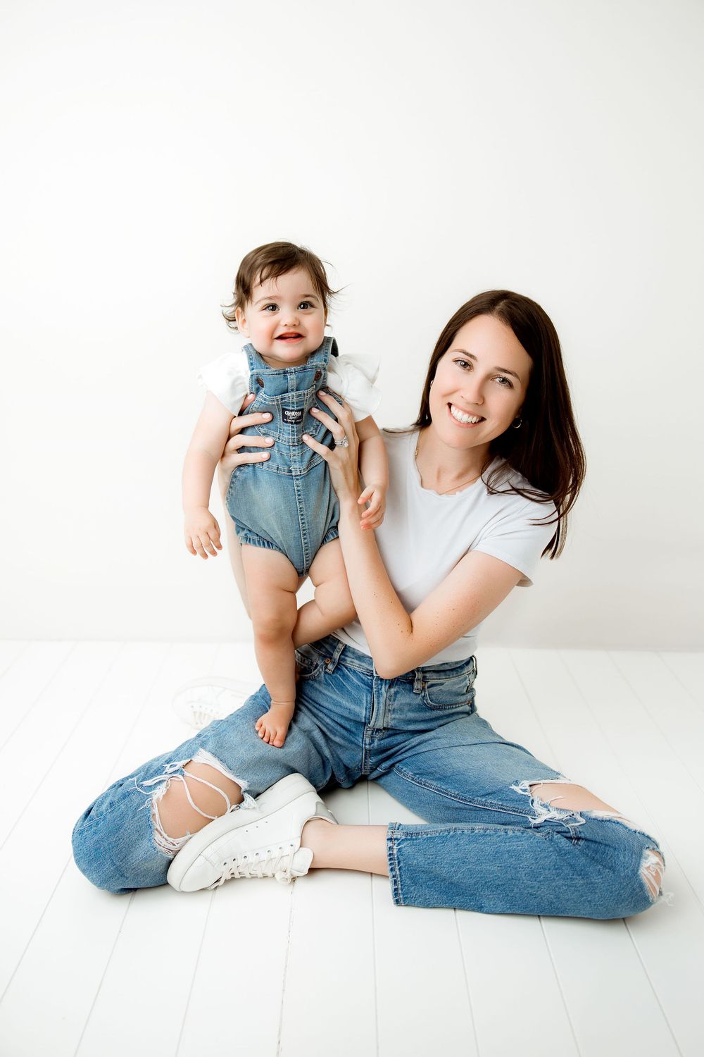 mom and baby sitting on the floor,  baby standing on mom's leg
