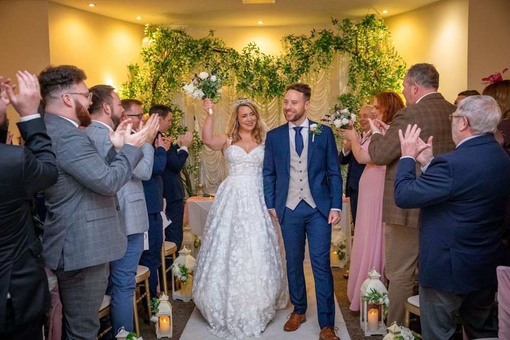 Newlyweds walking back down the aisle to applause after their wedding ceremony.