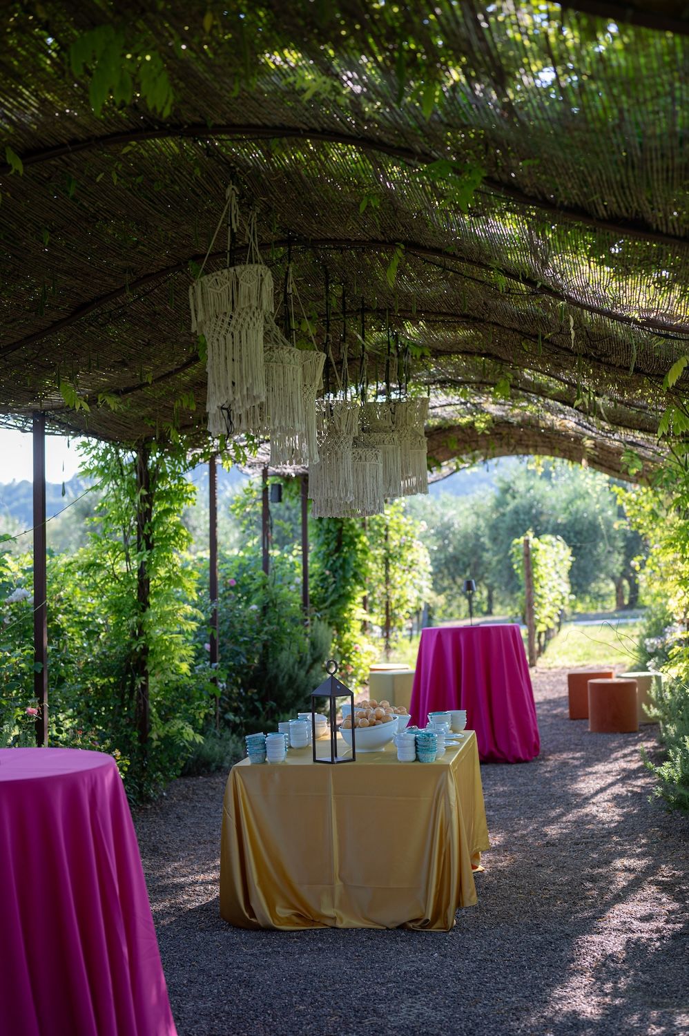 Colorful Indian textiles and bright linens decorating a rustic Italian wine resort garden.
