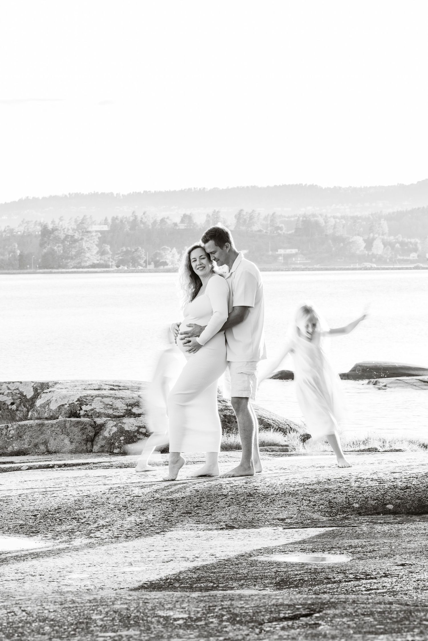 A romantic black and white photo sequence showing a couple in white attire dancing together by the water's edge.
