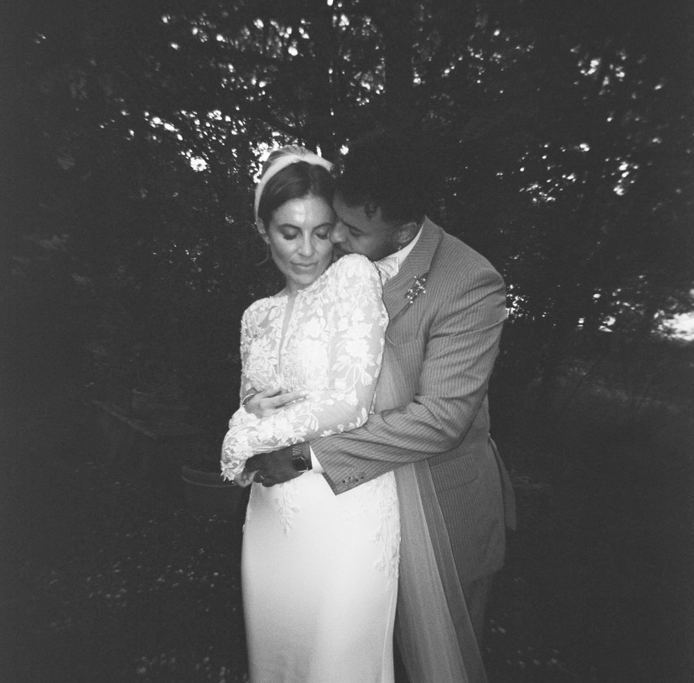 Black and white photo of a bride and groom embracing outdoors on their wedding day.