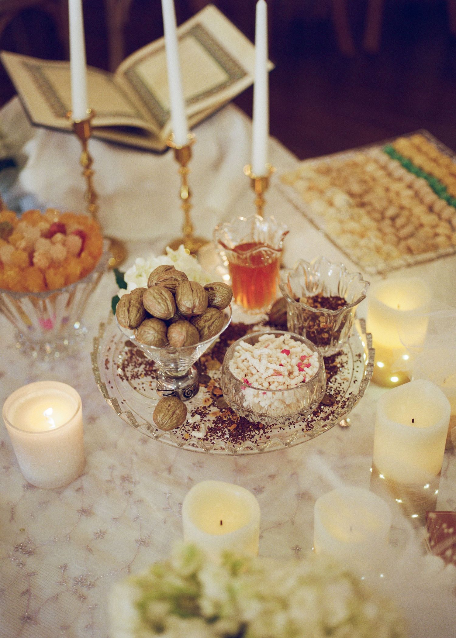 Traditional Persian wedding Sofreh Aghd table with candles, walnuts, and sweets.