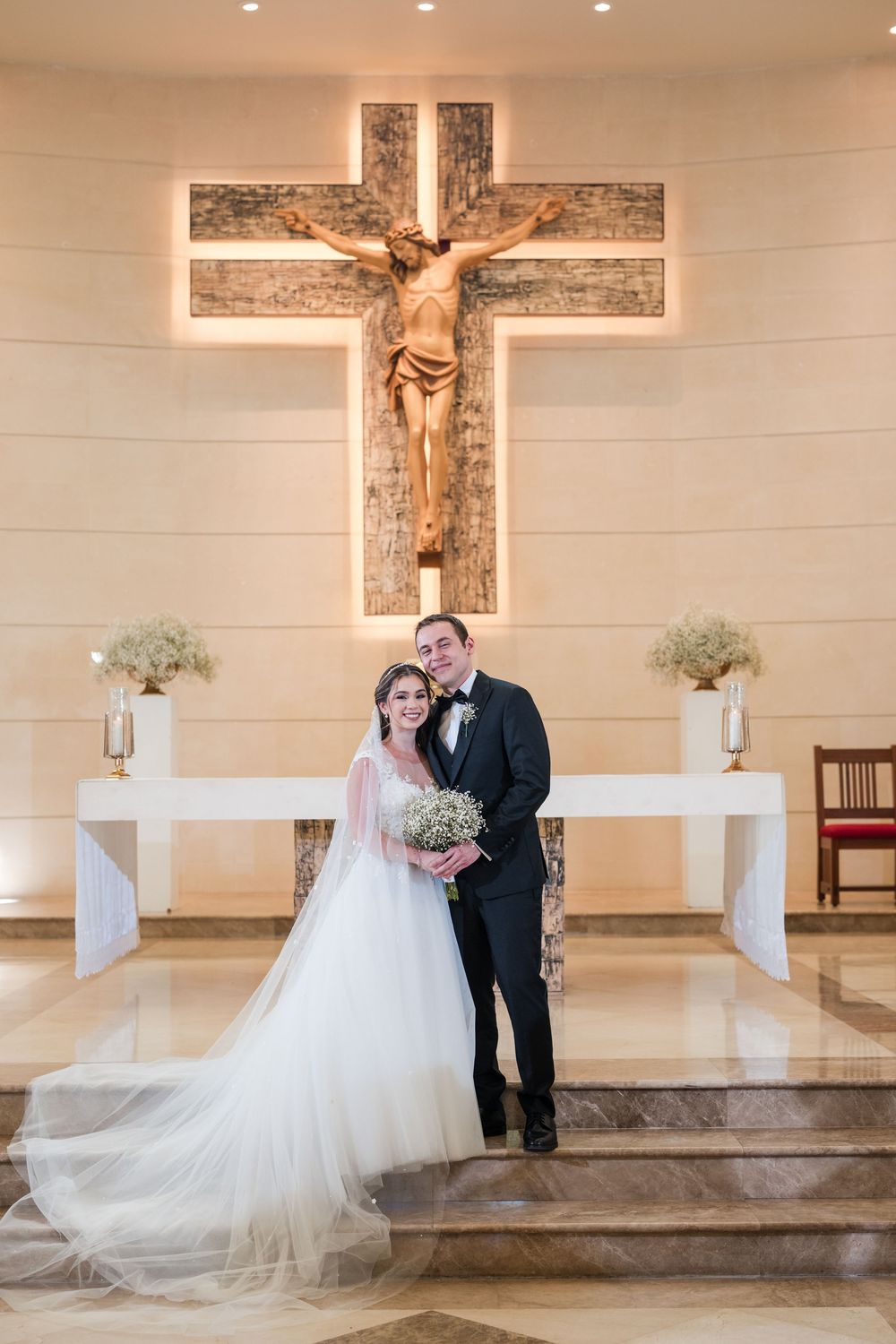 Bride and groom standing at altar under cross during ceremony at Stella Maris Church