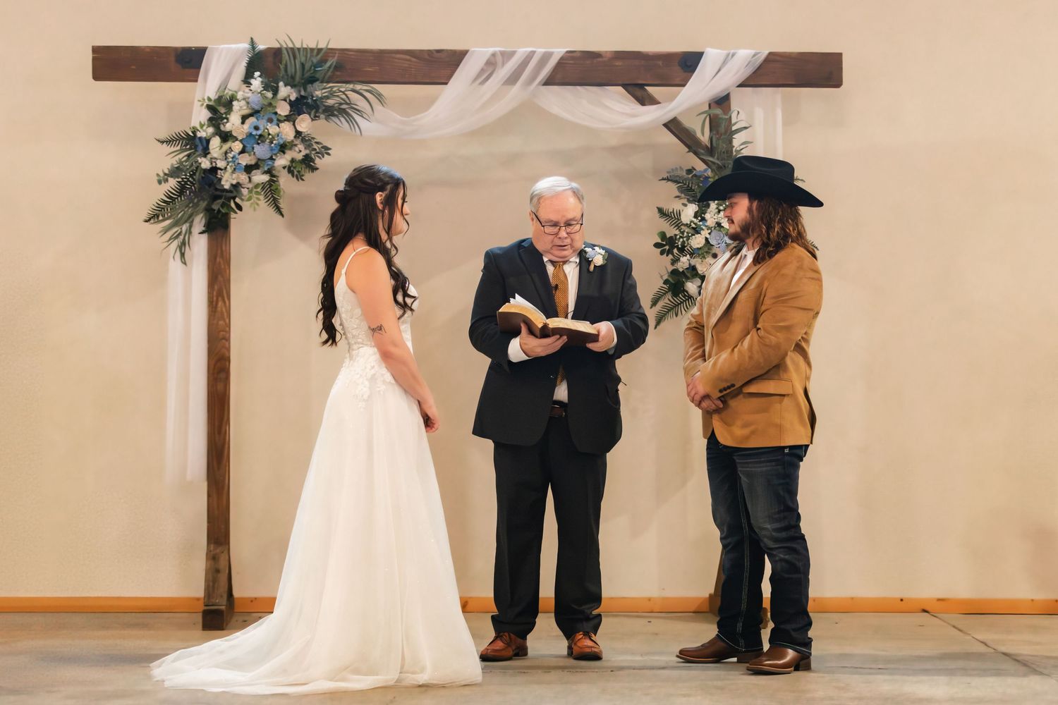 People dancing and celebrating at a lively indoor wedding reception party with warm lighting and high ceilings.