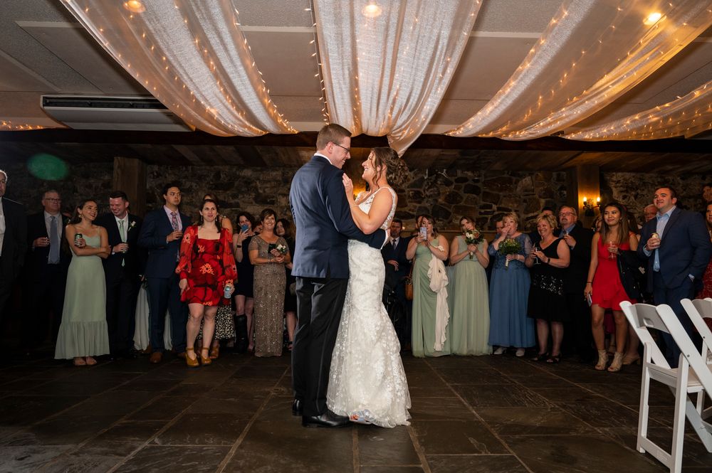 Couples dancing and celebrating at an elegant wedding reception under crystal chandeliers and draped fabric decor.