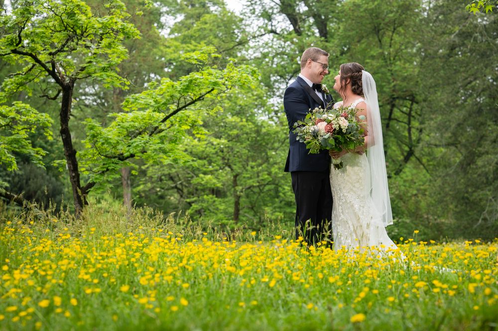 A couple shares a romantic moment together in a lush green meadow filled with bright yellow wildflowers.