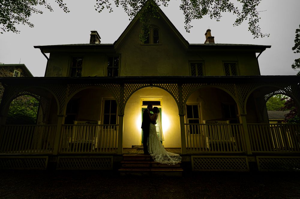 String lights illuminate the exterior of a rustic farmhouse at dusk creating a warm, inviting ambiance.