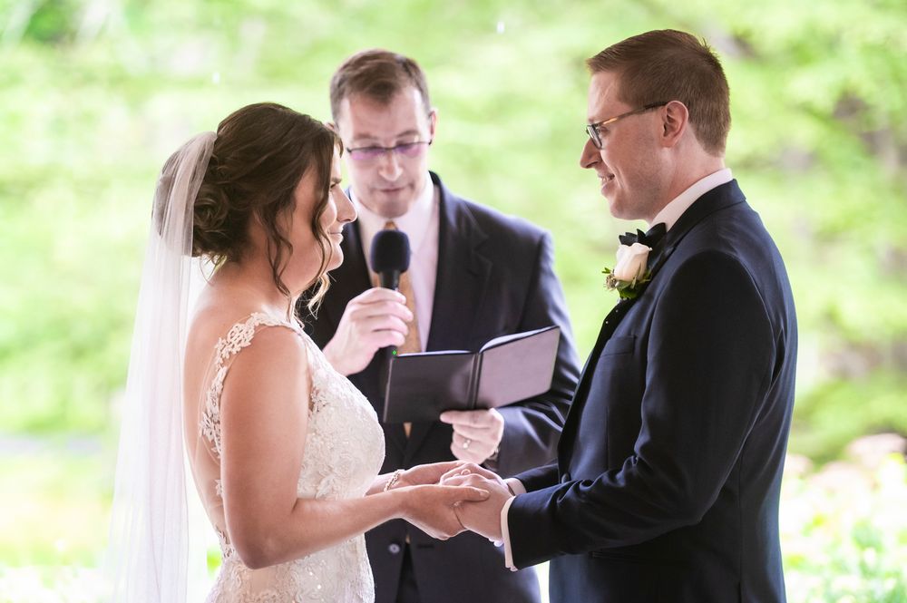 Wedding ceremony taking place outdoors with lush green foliage in the background.