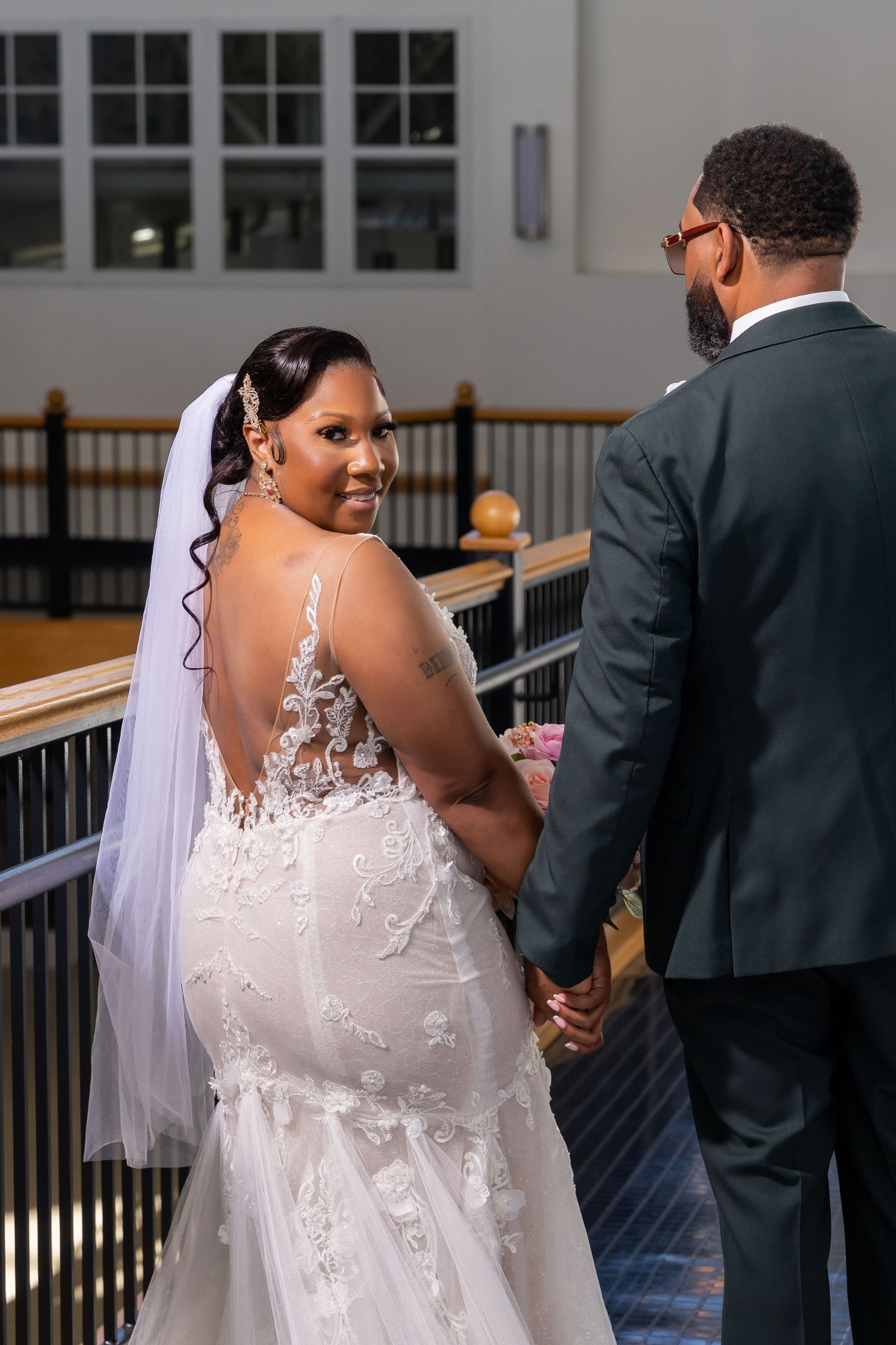 A couple walks together during their wedding ceremony, with the bride wearing a white lace dress with delicate back details.