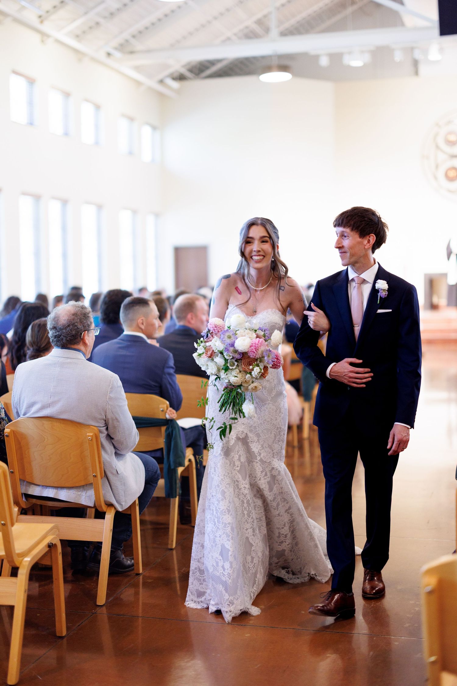 A bride and groom share a joyful moment with guests during their wedding ceremony in a bright, airy venue.