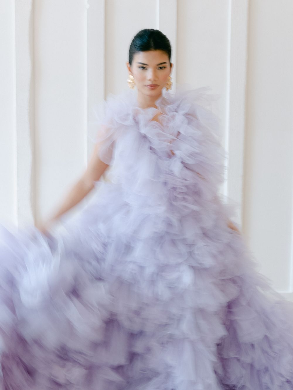 Ethereal lavender tulle gown with dramatic ruffles and volume photographed against a white backdrop.