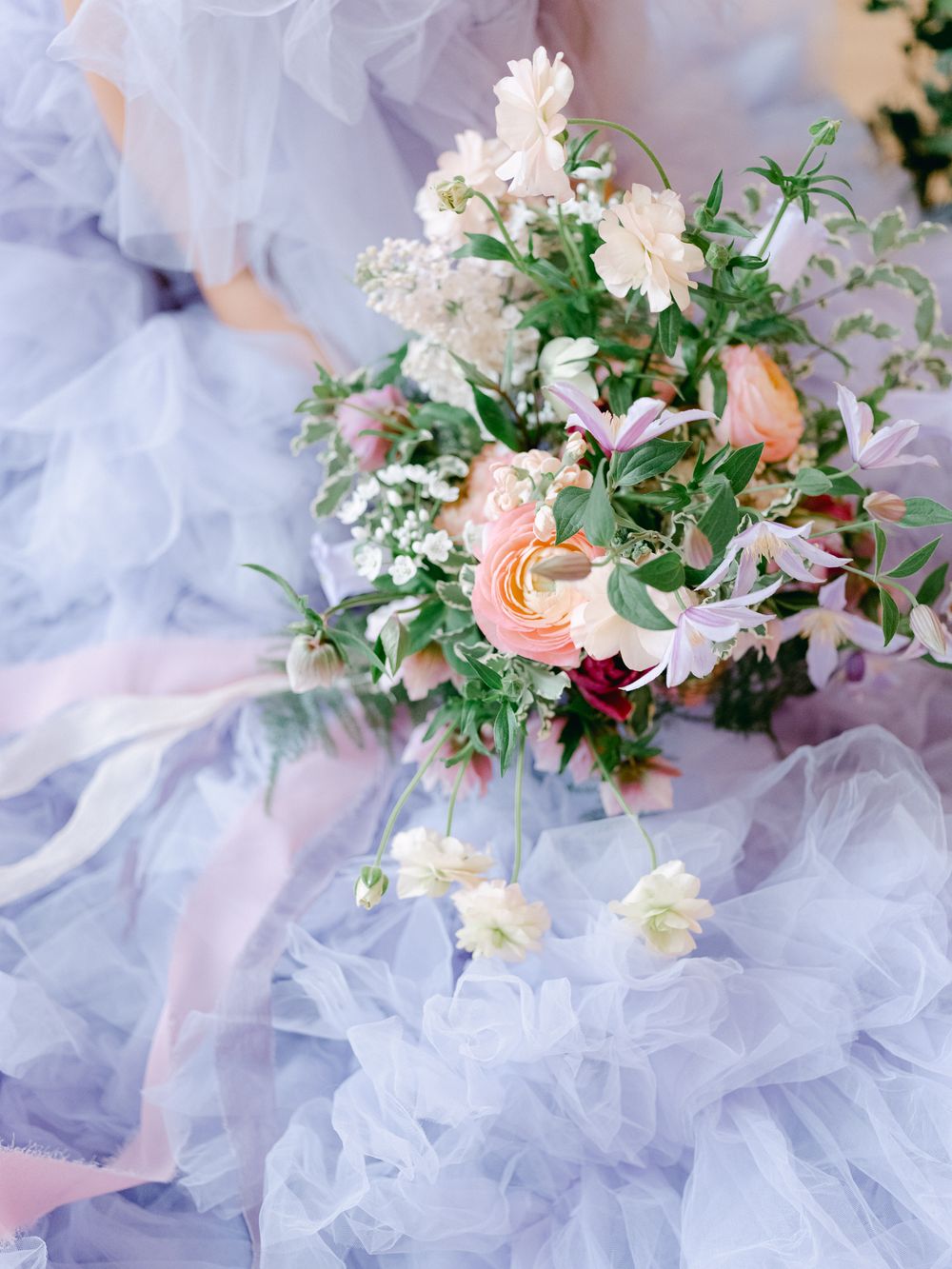 Romantic floral bouquet with pink and white blooms nestled among soft tulle fabric.