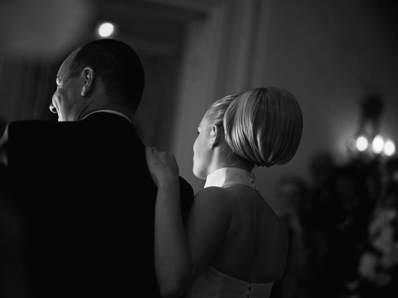 Elegant wedding couple from behind during a French chateau reception, captured in a soft bw editorial style with atmospheric light