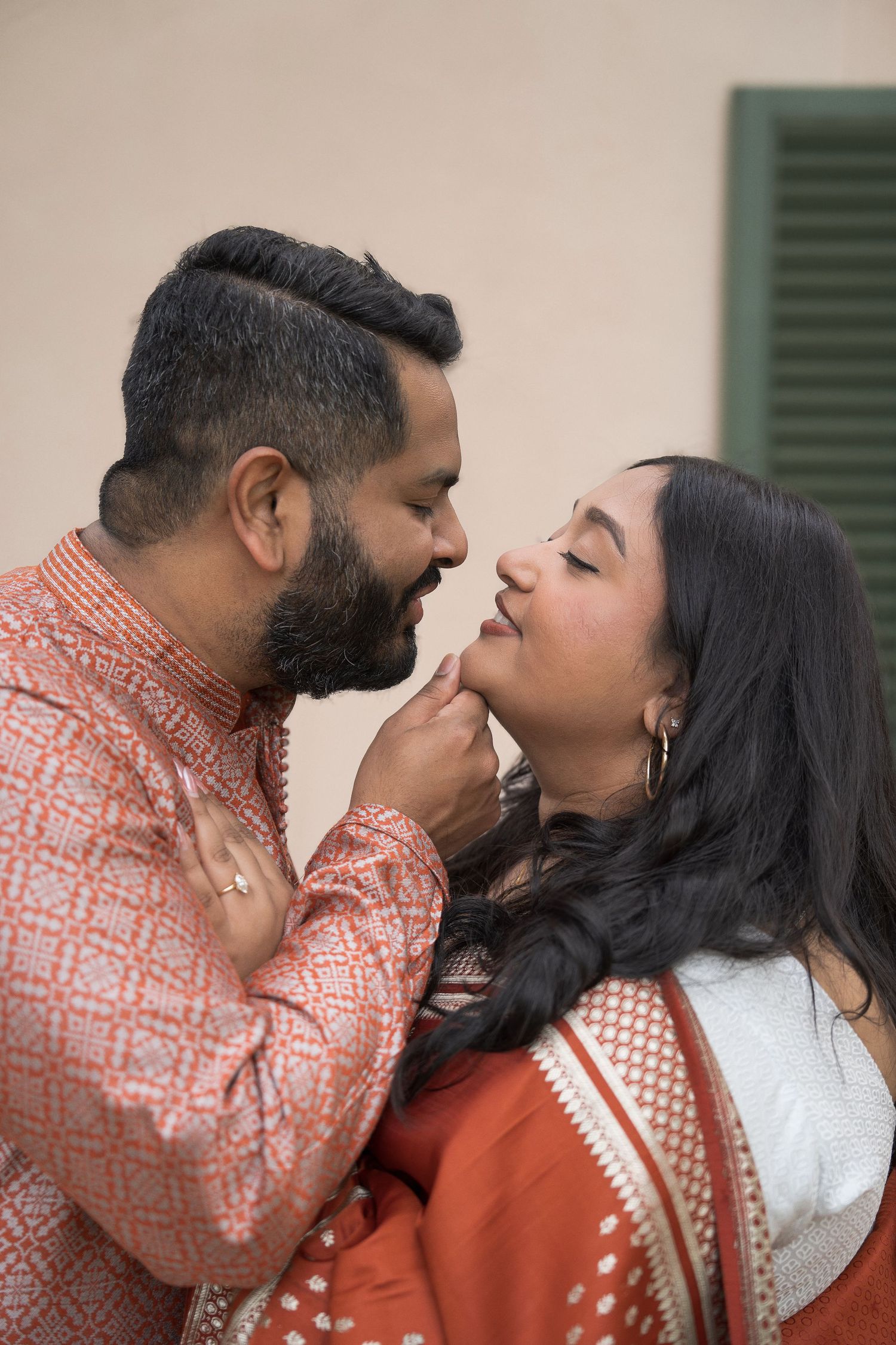 Indian couple in traditional attire sharing a romantic moment, man gently touching woman's chin.
