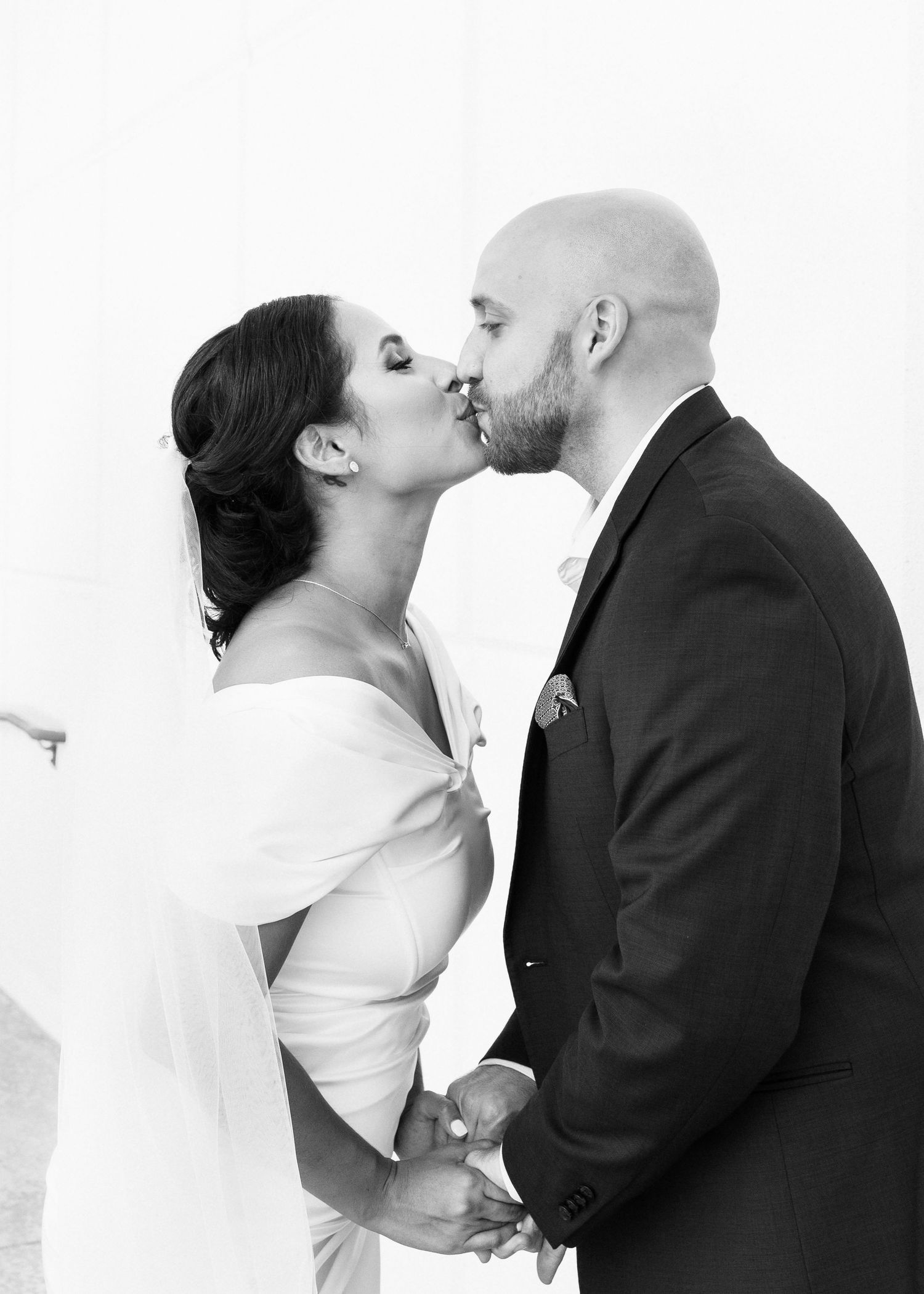 A couple shares a romantic kiss in three similar black and white wedding photos.