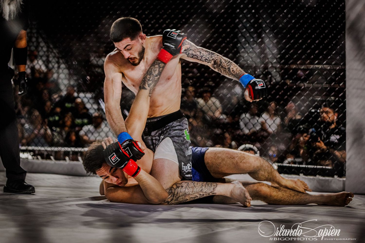Two MMA fighters grappling on the mat during an intense mixed martial arts competition match.
