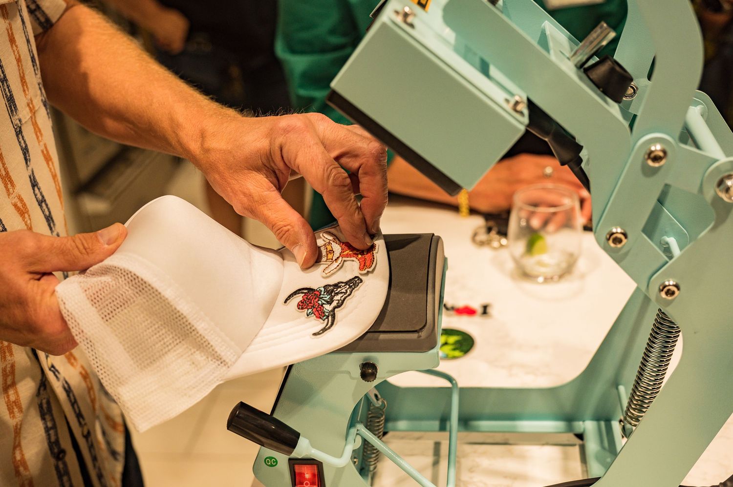 Close-up of hands using a heat press machine to transfer a colorful design onto white fabric.