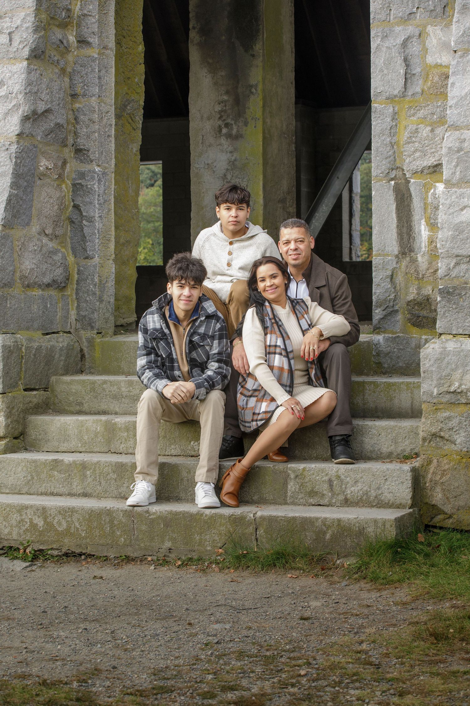 A group seated on stone steps in a rustic outdoor setting wearing casual fall attire.